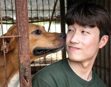 Sangkyung Lee, Dog Meat Campaign Manager of HSI Korea, interacts with a dog at a dog meat farm